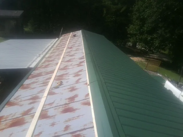 Old rusted panels beside newly installed green metal roofing — Wind Damage Roof Repair by Roofing Brothers in Custer City