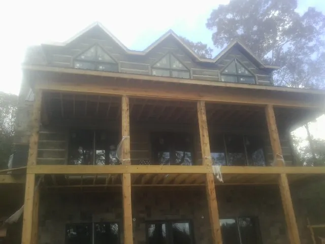 Dormers and porch framing on a large log home under construction — Roof Coating work by our crew in Custer City