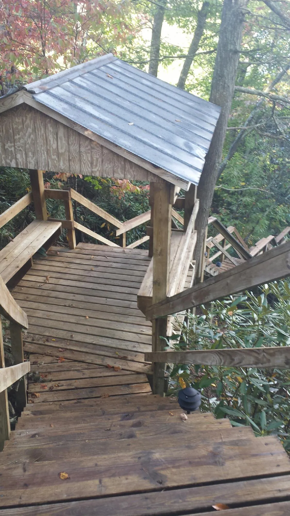 Metal roofed shelter over wooden steps on a wooded walkway — Skylight Repair & Installation work by our crew in Custer City