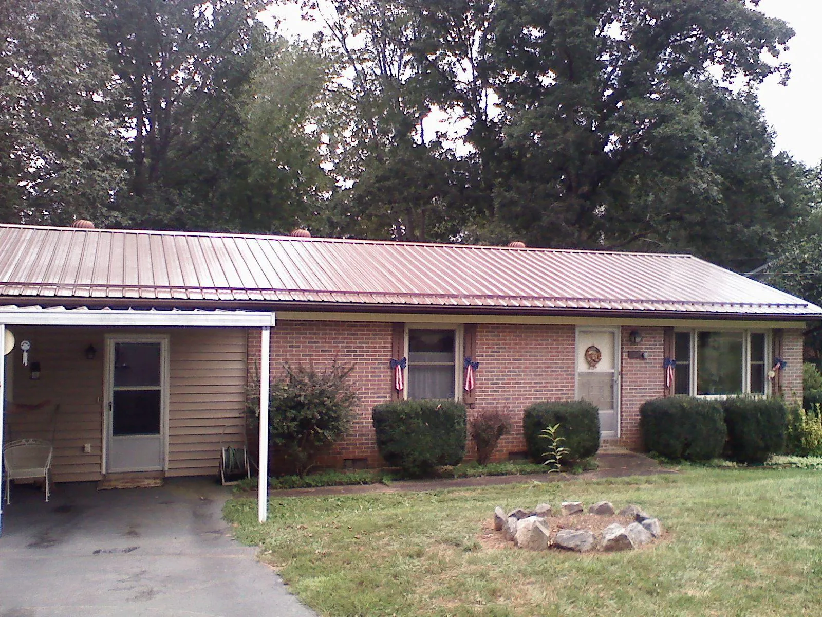 Bronze metal roof and carport on a brick ranch home — Roof Repair work by our crew in Custer City