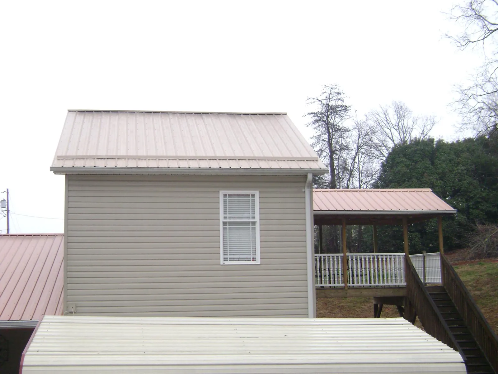 Tan metal roofs on a two story addition and attached porch, from a Roof Replacement job in Custer City